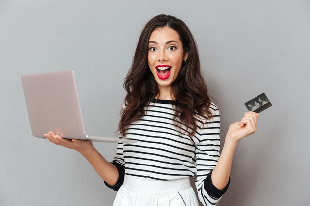 Porträt einer aufgeregten Frau, die Laptop-Computer hält