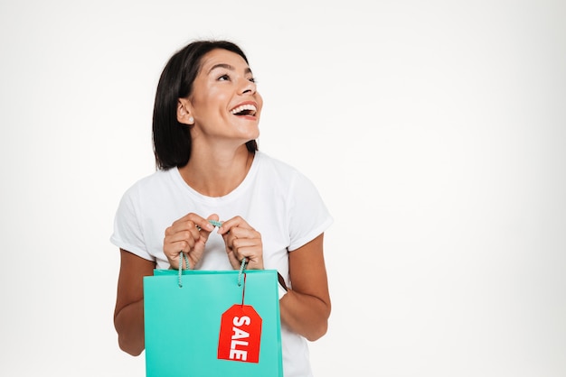 Porträt einer aufgeregten glücklichen hübschen Frau, die Einkaufstasche hält