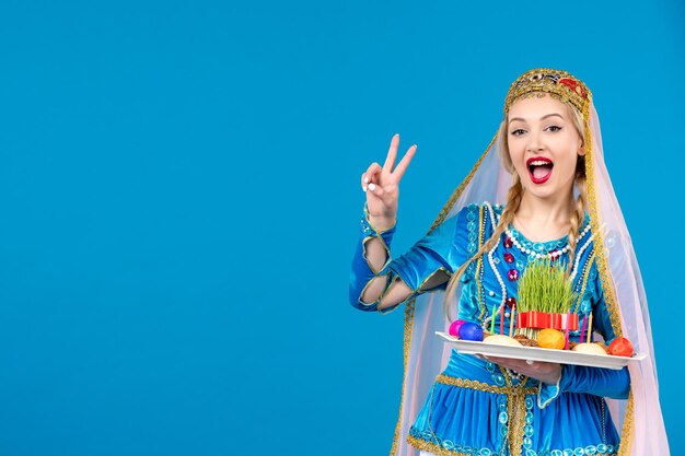 Porträt einer azerinischen Frau in traditioneller Kleidung mit Novruz Xonca blauem Hintergrund Frühlingsfarbe ethnische Geldtänzerin