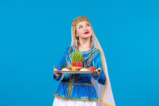 Porträt einer azerinischen Frau in traditioneller Kleidung mit Novruz Xonca Studio schoss blaue Hintergrundfarbe Frühlingskonzept ethnische Tänzerin