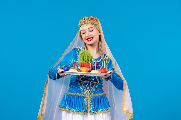 Porträt einer azerinischen frau in traditioneller kleidung mit novruz-xonca-studioaufnahme mit blauem hintergrund ethnischer frühlingstänzerfarben