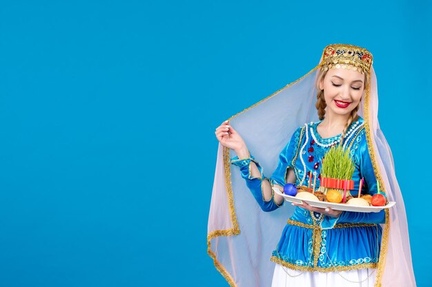Porträt einer azerinischen Frau in traditioneller Kleidung mit Xonca auf blauem Hintergrund Frühlingskonzept Novruz-Tänzerin ethnisch