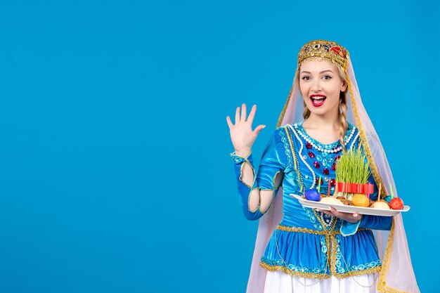 Porträt einer azerinischen Frau in traditioneller Kleidung mit Xonca aufgeregt auf blauem Hintergrund ethnischer Frühlingstänzer novruz