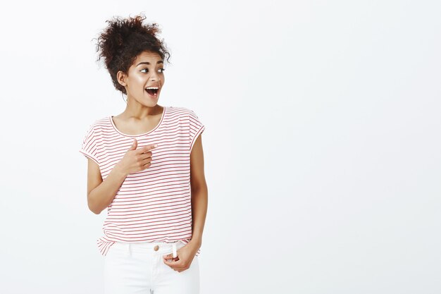 Porträt einer beeindruckten Frau mit Afro-Frisur, die im Studio aufwirft