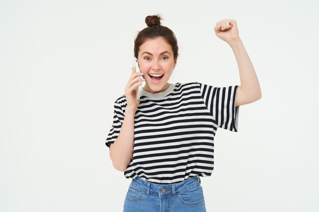 Porträt einer begeisterten jungen Frau, die mit dem Handy spricht, den Anruf antwortet und singt