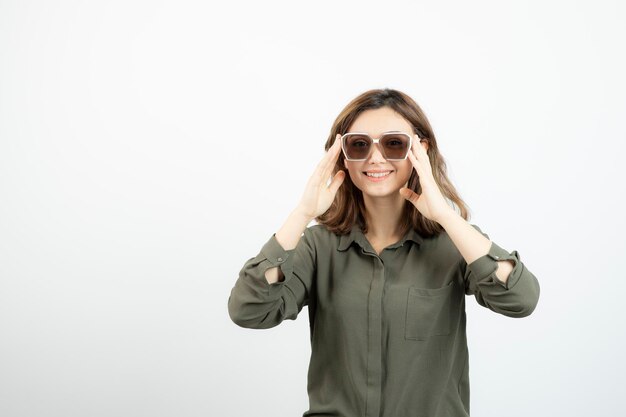 Porträt einer entzückenden jungen Frau mit Brille, die über Weiß steht. Foto in hoher Qualität