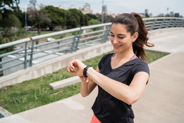 Porträt einer Fitnessfrau, die Zeit auf ihrer intelligenten Uhr prüft. Sport und gesunder Lebensstil Konzept.