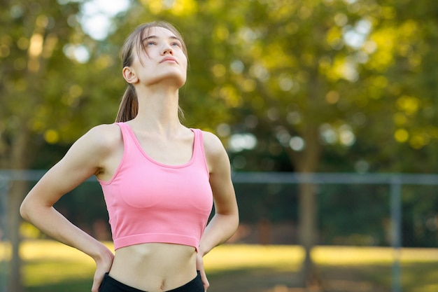 Porträt einer fitten jungen Dame, die ihre Hände auf ihre Taille legte und nach oben schaute