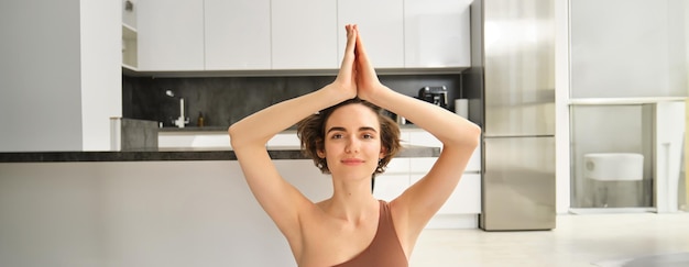 Kostenloses Foto porträt einer fitten und gesunden frau in sportbekleidung, die zu hause yoga auf einer fitnessmatte macht