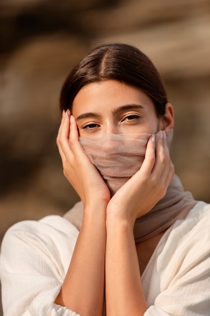 Kostenloses Foto porträt einer frau am strand, die ihr gesicht hinter einem schleier versteckt