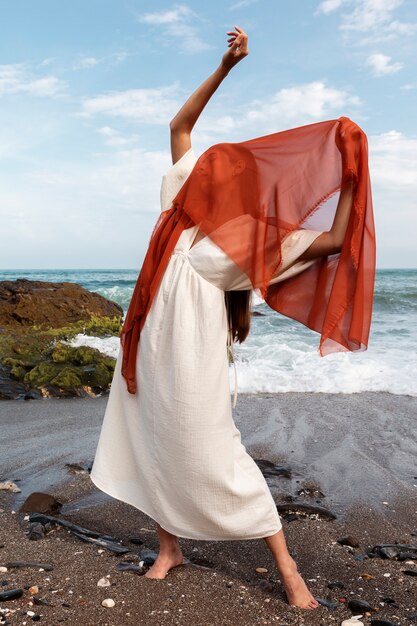 Porträt einer Frau am Strand, die ihr Gesicht mit einem Schleier bedeckt