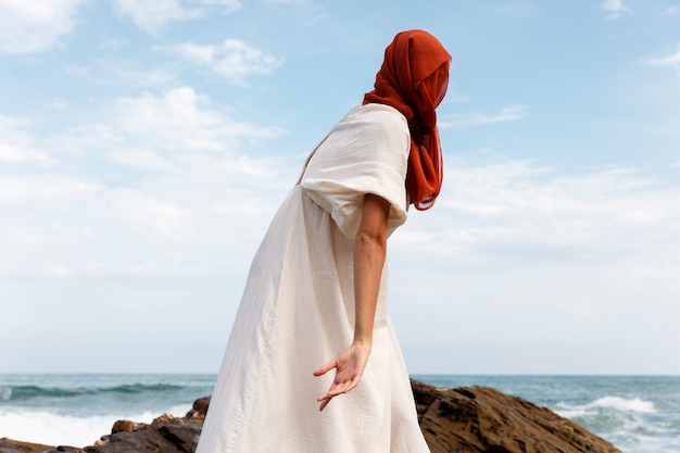 Porträt einer Frau am Strand, die ihr Gesicht mit einem Schleier bedeckt