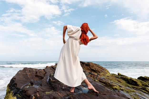 Porträt einer Frau am Strand, die ihr Gesicht mit einem Schleier bedeckt