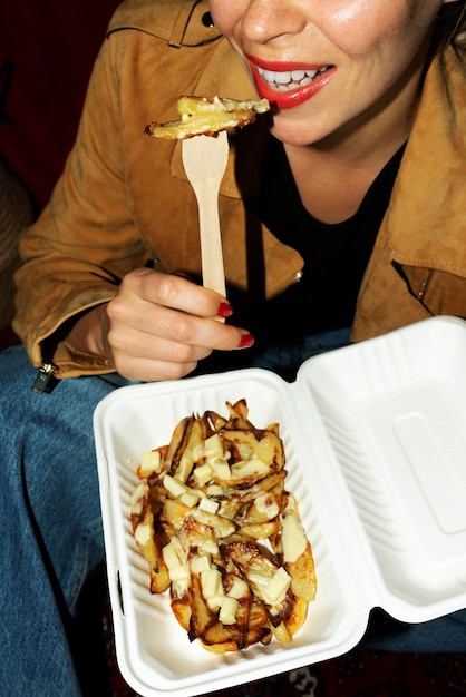 Porträt einer Frau, die ein Gericht mit Poutine isst