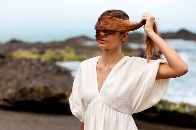 Porträt einer Frau, die ihr Gesicht mit Haaren am Strand bedeckt