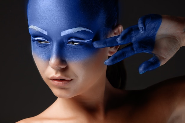 Porträt einer Frau, die mit blauer Farbe bedeckt posiert
