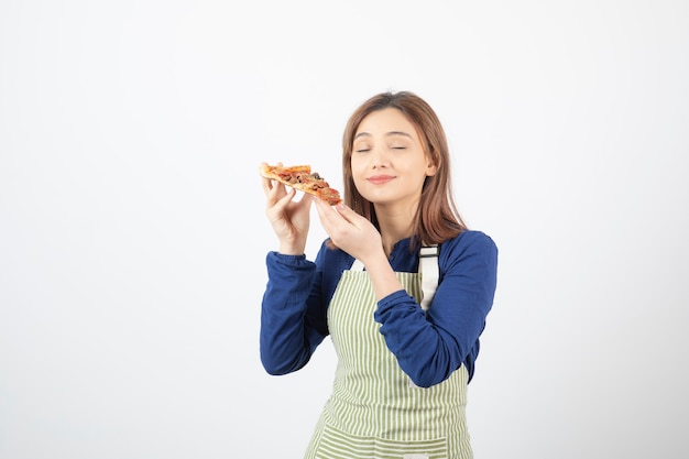 Porträt einer Frau in Schürze posiert mit einem Stück Pizza auf weiß