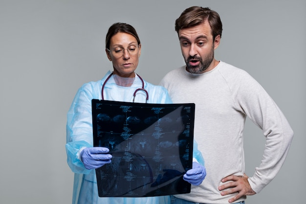 Porträt einer Frau mit Arztkittel, die einen CT-Scan des Patienten zeigt