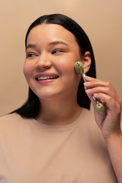 Kostenloses Foto porträt einer frau mit jade-roller auf ihrem gesicht