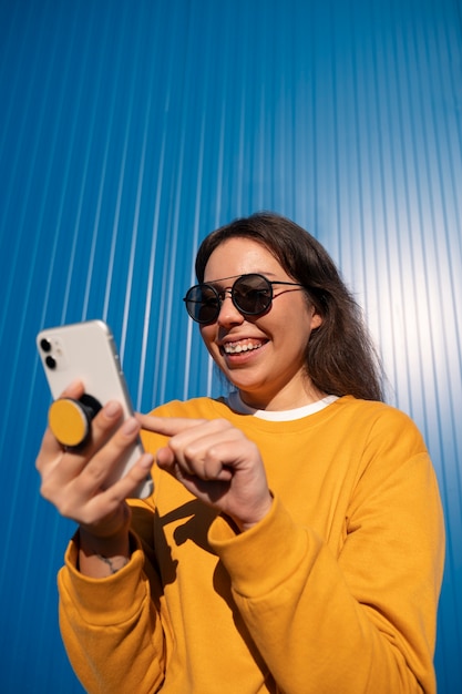 Kostenloses Foto porträt einer frau mit smartphone mit pop-socket im freien