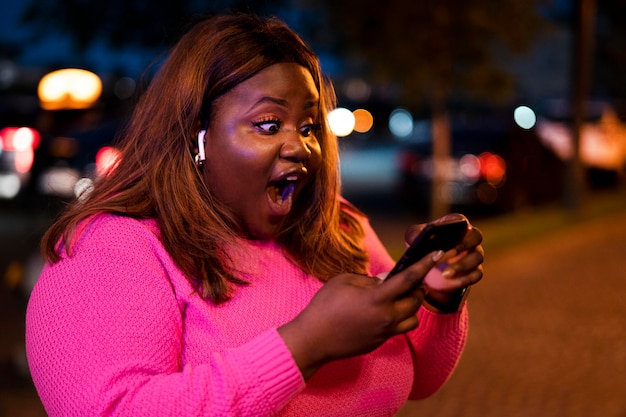 Kostenloses Foto porträt einer frau mit smartphone nachts in den lichtern der stadt city