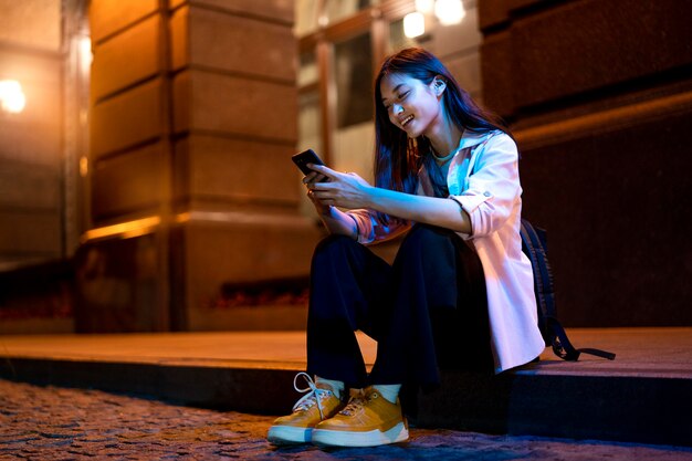 Porträt einer Frau mit Smartphone nachts in den Lichtern der Stadt city