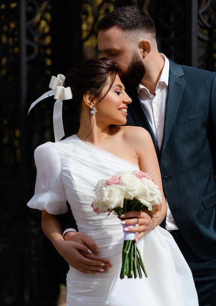 Porträt einer fröhlichen Frau mit Frisur, die ein schulterfreies Kleid trägt und auf der anderen Seite einen Strauß weißer und rosafarbener Rosen lächelnd hält