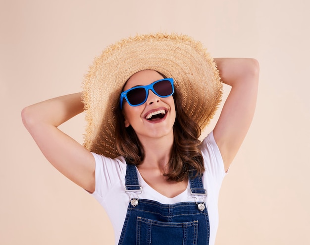 Porträt einer fröhlichen Frau mit Sonnenbrille und Sonnenhut