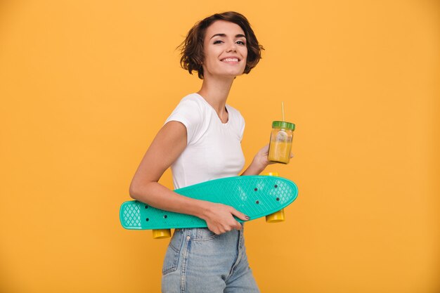 Porträt einer fröhlichen jungen Frau, die Skateboard hält