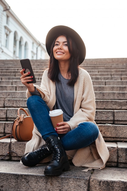 Porträt einer fröhlichen lächelnden frau, die auf handy schreibt