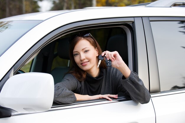 Porträt einer glücklichen erfolgreichen Frau mit Schlüsseln vom neuen Auto - draußen