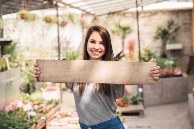 Kostenloses Foto porträt einer glücklichen frau, die hölzerne planke hält