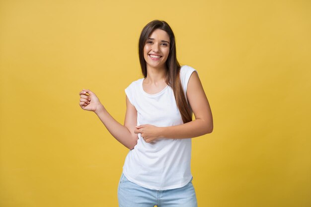 Porträt einer glücklichen jungen Frau, die auf gelbem Hintergrund tanzt