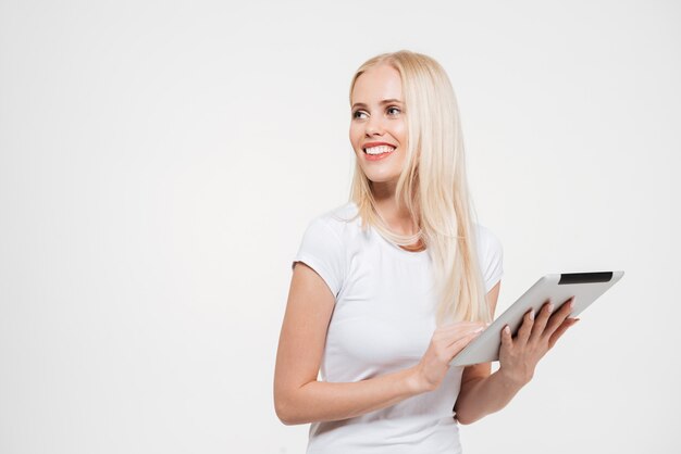 Porträt einer glücklichen lächelnden blonden Frau, die Tablet-Computer hält