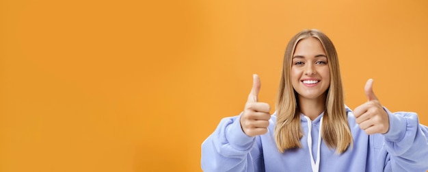 Kostenloses Foto porträt einer glücklichen optimistischen frau, die daumen nach oben zeigt und mit fröhlichem lo lächelt