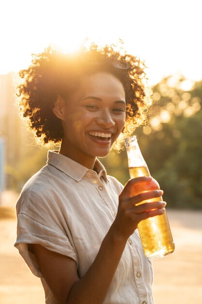 Porträt einer glücklichen Smiley-Frau draußen im Sonnenlicht mit Bier