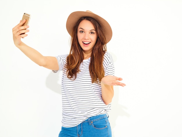 Porträt einer hübschen Frau im Sommerhippie kleidet das Nehmen eines selfie, das auf weißer Wand lokalisiert wird