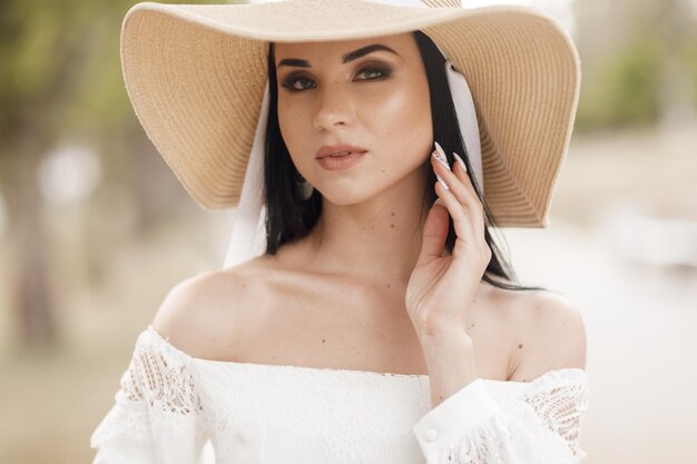 Porträt einer hübschen jungen Frau mit Hut und Kleid im Freien