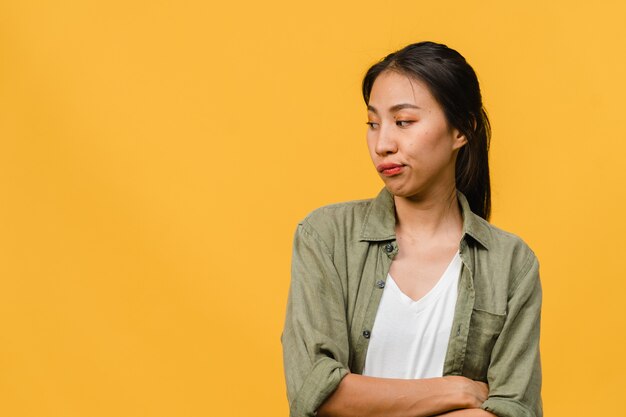 Porträt einer jungen asiatischen Dame mit negativem Ausdruck, aufgeregtem Schreien, weinen emotional wütend in Freizeitkleidung einzeln auf gelber Wand mit leerem Kopienraum. Gesichtsausdruck Konzept.