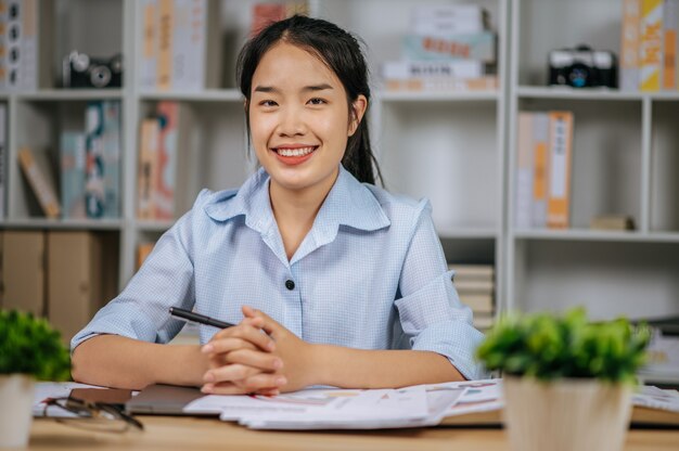 Porträt einer jungen asiatischen Freiberuflerin, die mit Papieren am Arbeitsplatz im Homeoffice arbeitet, während der Quarantäne-Kovid-19-Selbstisolation zu Hause, von zu Hause aus arbeiten Konzept