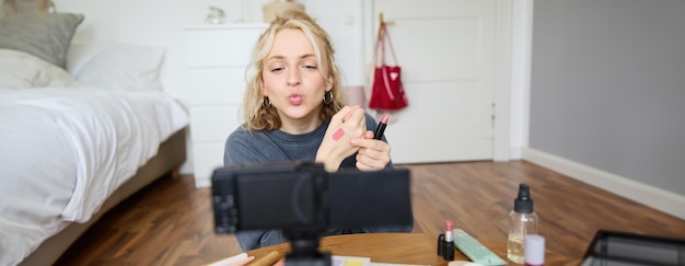 Kostenloses Foto porträt einer jungen bloggerin mit lippenstiftproben auf der hand