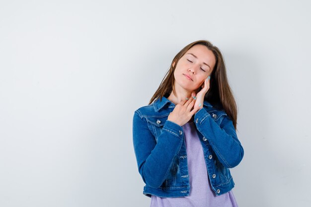 Porträt einer jungen Dame, die die Gesichtshaut auf der Wange in T-Shirt, Jacke untersucht und entspannte Vorderansicht schaut