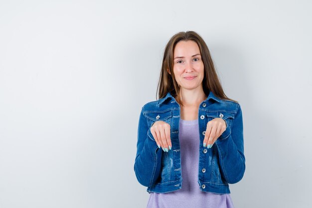 Porträt einer jungen Dame, die Hände als Pfoten über der Brust in T-Shirt, Jacke hält und fröhliche Vorderansicht sieht