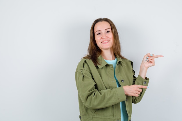 Porträt einer jungen Dame, die in T-Shirt, Jacke und glücklicher Vorderansicht auf die rechte Seite zeigt