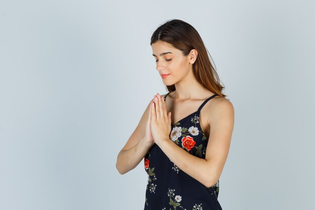 Porträt einer jungen Dame mit Namaste-Geste in Bluse und hoffnungsvoller Vorderansicht