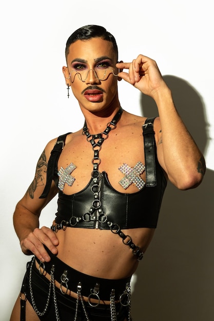 Porträt einer jungen drag queen mit schwarzem ledergeschirr auf weißem hintergrund Premium Fotos
