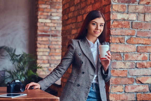 Porträt einer jungen Fotografin hält eine Tasse eines Morgens