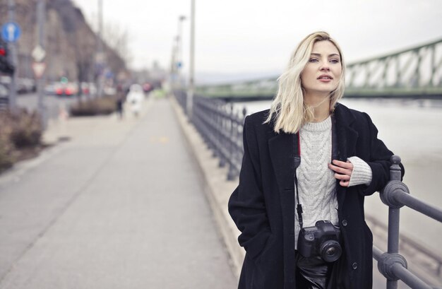 Porträt einer jungen Frau auf einer Brücke mit einer Digitalkamera