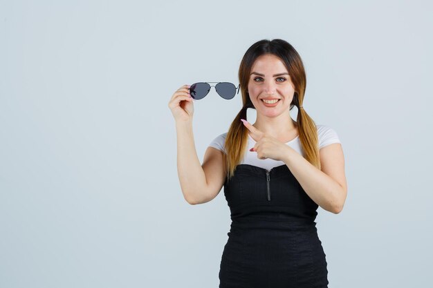 Porträt einer jungen Frau, die auf eine Brille zeigt