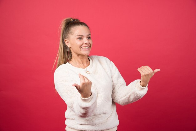 Porträt einer jungen Frau, die auf einer roten Wand steht und aufwirft